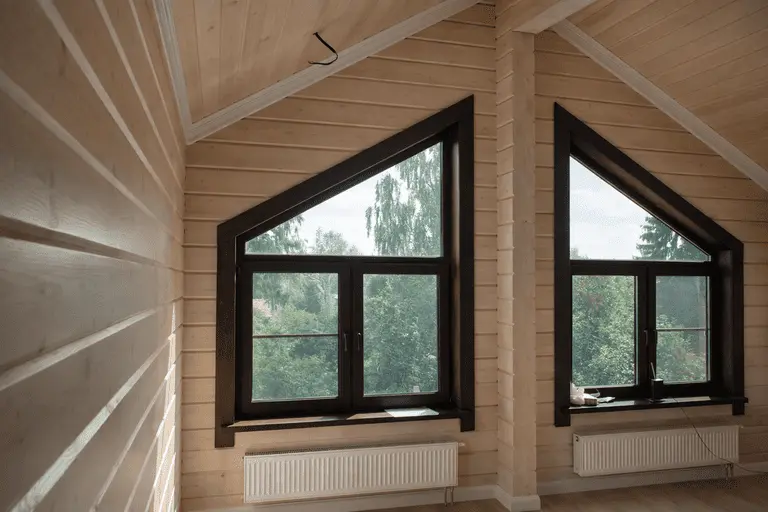Трапециевидные окна нестандартной формы под скатной крышей деревянного дома